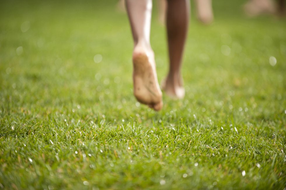 childs feet running on grassy lawn