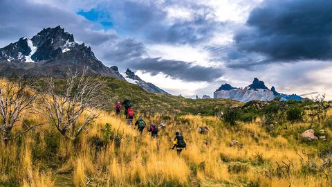 Een groep wandelaars trekt over de grasvlakten van het Parque Nacional Torres del Paine Omdat het weer hier snel kan omslaan moeten bezoekers zich goed voorbereiden met zonnebrandcrme en een warm en waterdicht jack