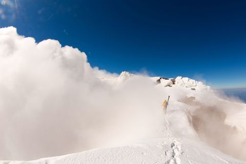 Op de top van een berg in het Merengebied van Chili loopt een skir met zijn uitrusting door een wolk In deze regio in het zuiden van Chili liggen talloze skioorden vanwaaruit wintersportliefhebbers routes kunnen verkennen die bij vulkaanuitbarstingen zijn gevormd