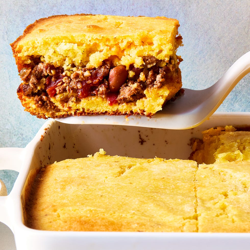 cornbread in a casserole dish with a layer of chili in the middle