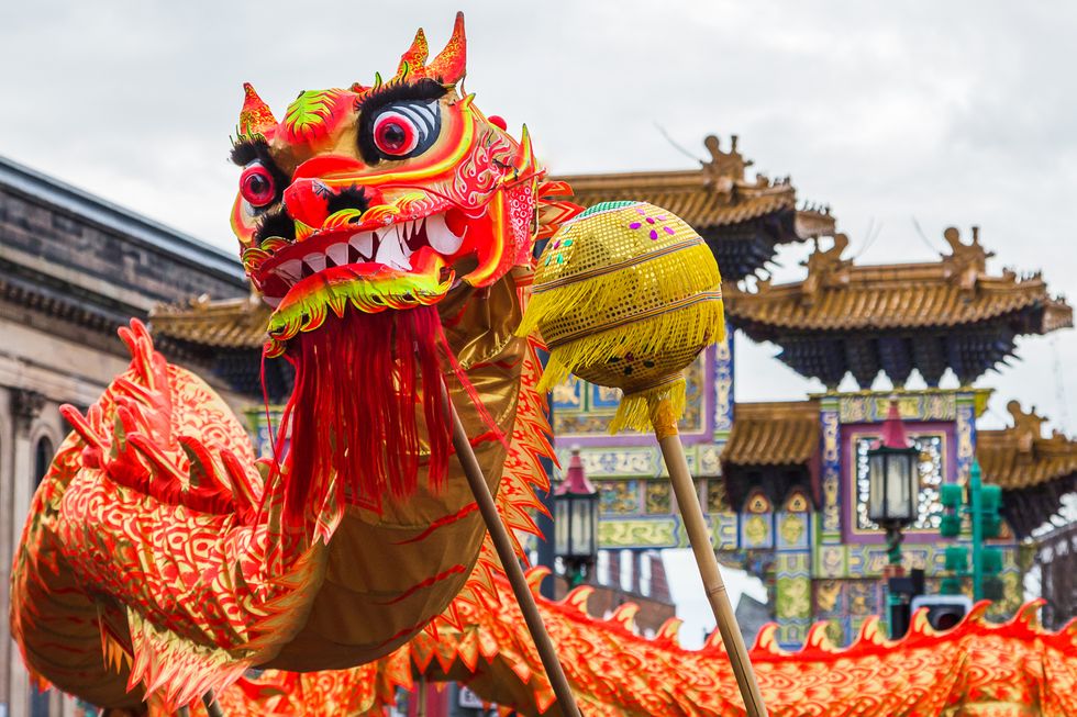 the pretty orange and red coloured dragon weaves through the crowds of people in liverpools chinatown chasing a pearl during chinese new year celebrations