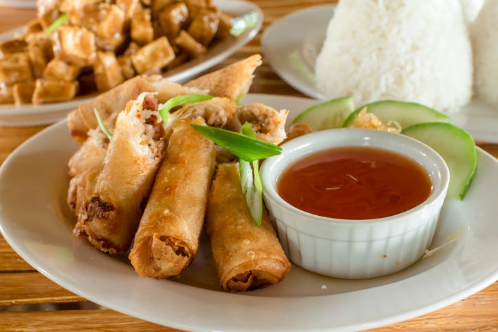 lumpiang shanghai, a filipino egg roll, with sizzling tofu and a cup of rice at the back philippine cuisine