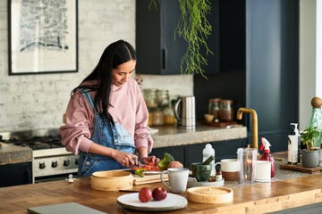 chinese woman prepares vegetable on kitchen worktop