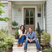 chip and joanna gaines in front of minty green home