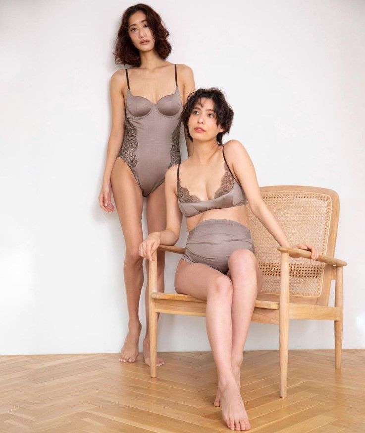 a woman standing next to another woman sitting on a chair