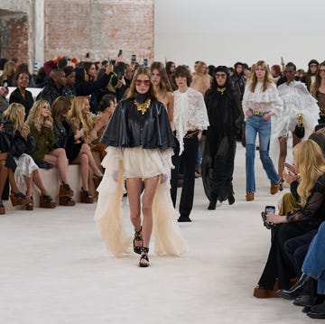 Fashion show runway featuring models in various outfits and an audience Fashion show runway featuring models in various outfits and an audience