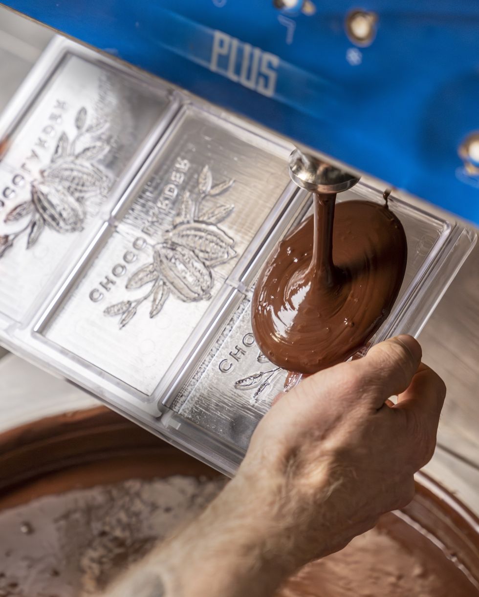 tempered chocolate being poured into plastic moulds at a chocolate factory