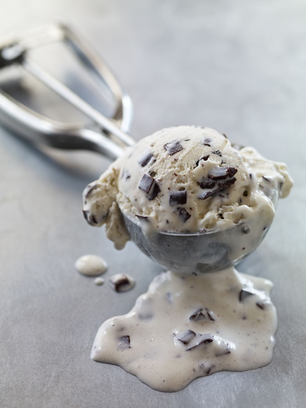 chocolate chip ice cream in metal scoop melting