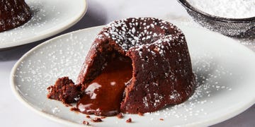 chocolate cake topped with powdered sugar sliced into with chocolate fudge spilling out