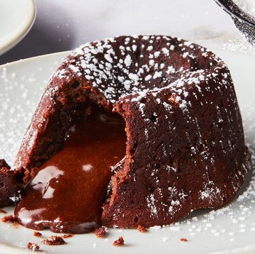 chocolate cake topped with powdered sugar sliced into with chocolate fudge spilling out