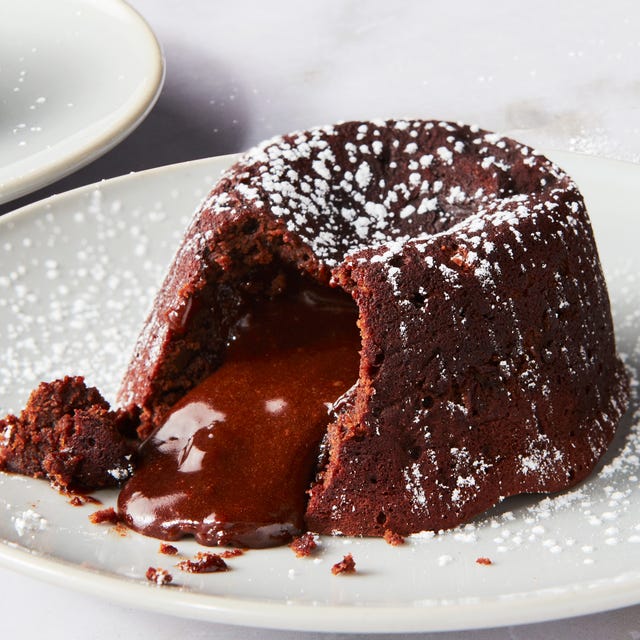 chocolate cake topped with powdered sugar sliced into with chocolate fudge spilling out