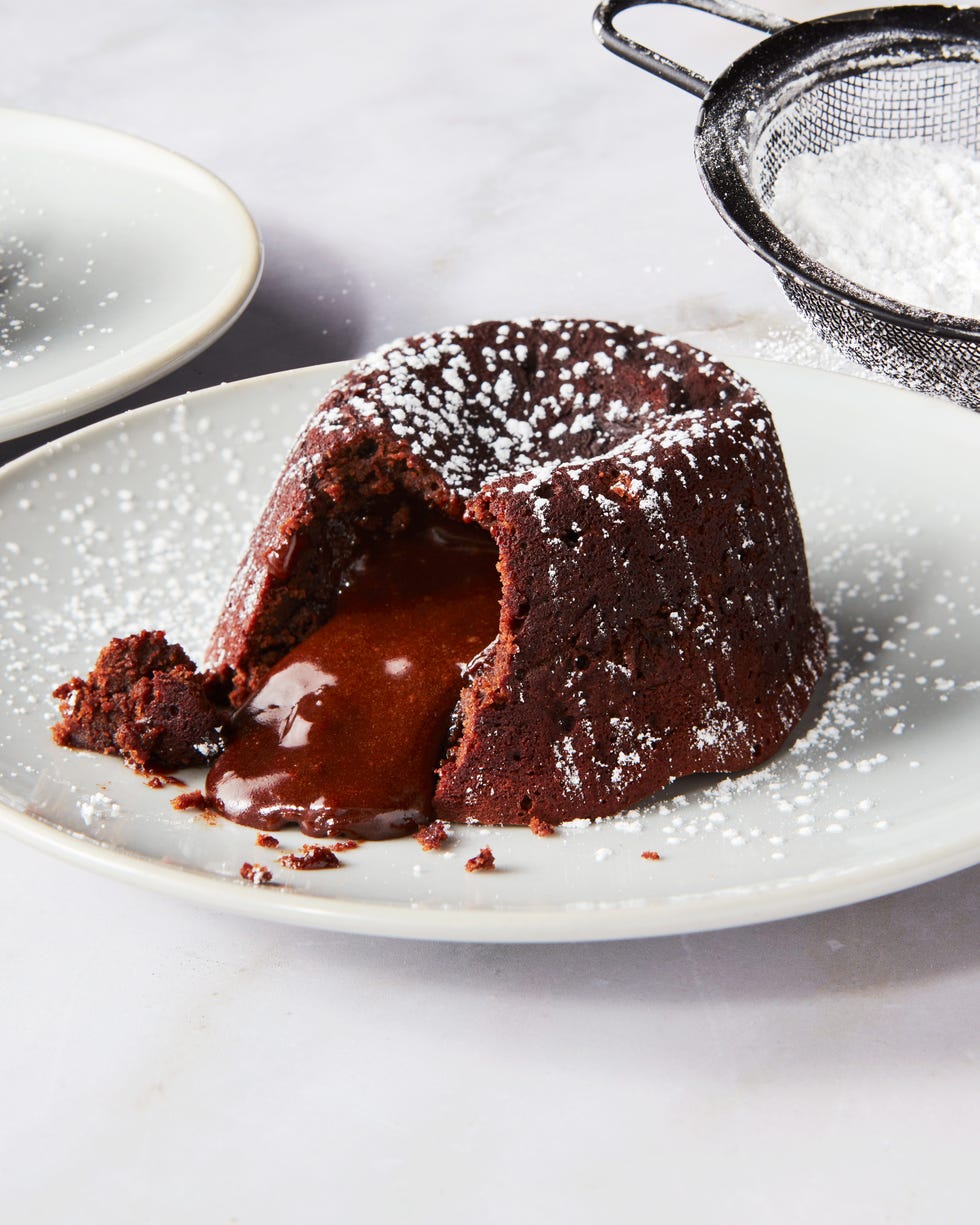 chocolate cake topped with powdered sugar sliced into with chocolate fudge spilling out