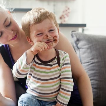 niño comiendo chocolate encima de su madre
