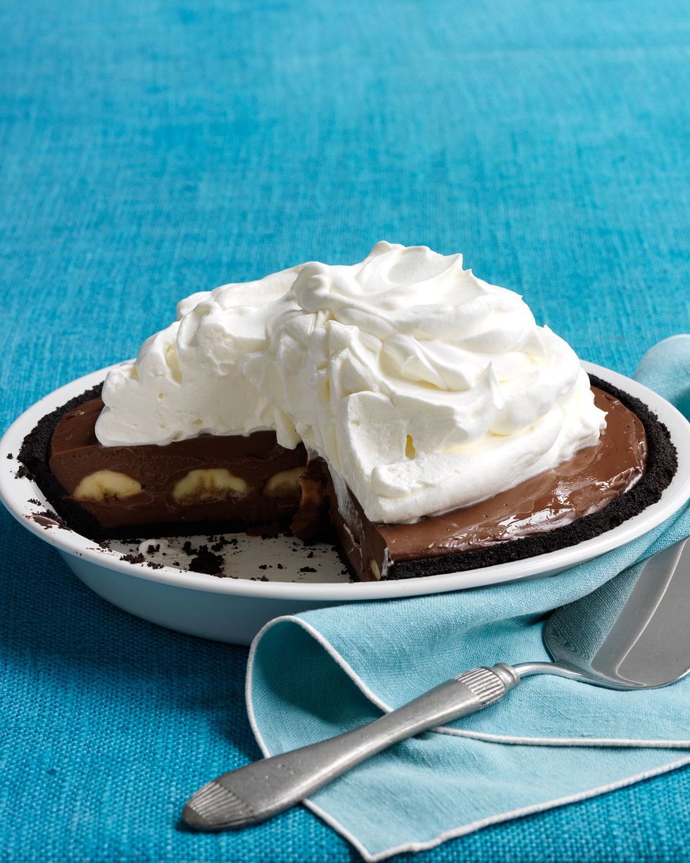 double chocolate banana cream pie in a white pie dish with whipped cream on top and a large slice removes to reveal the inside
