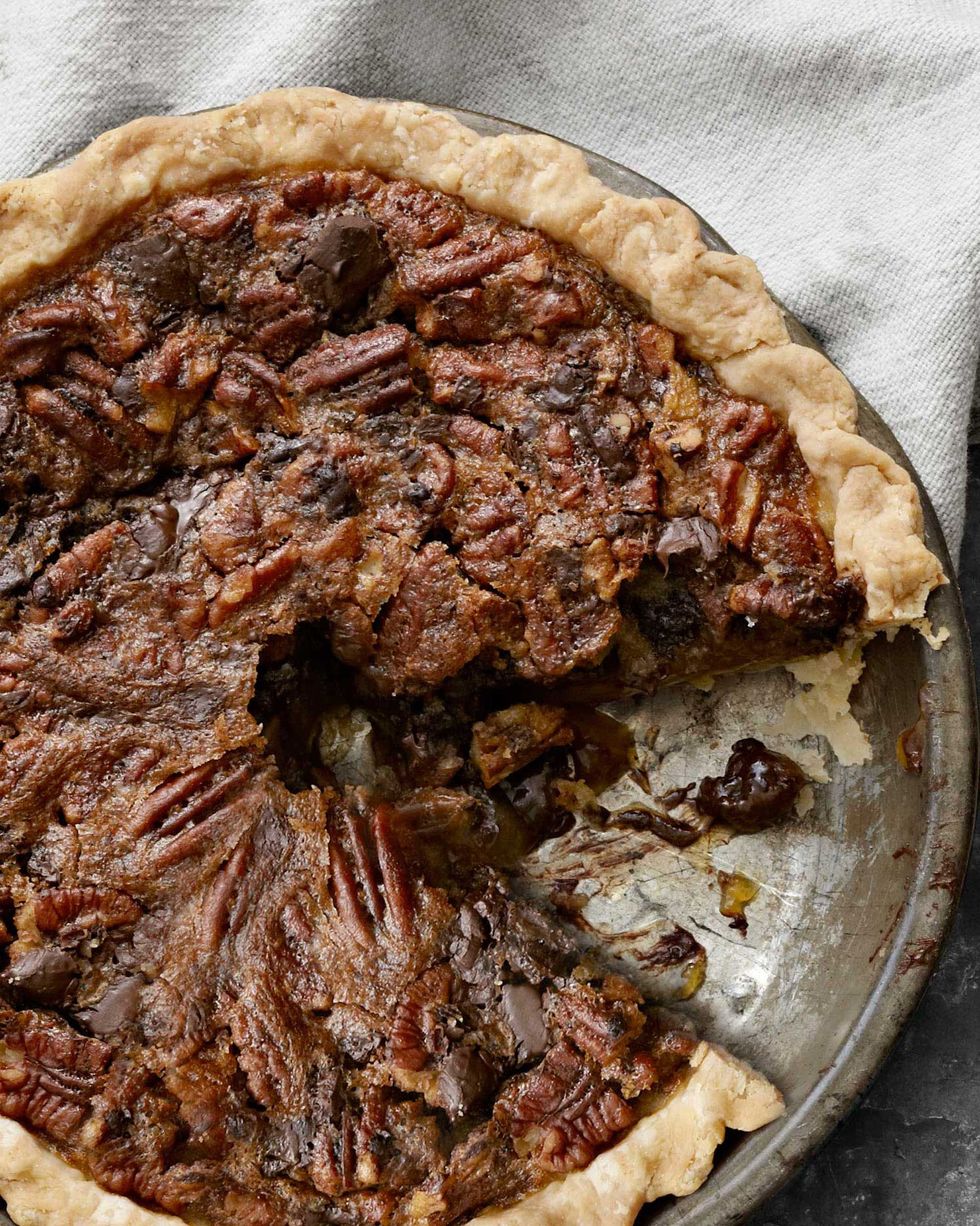 chocolate chunk pecan pie in a metal pie plate with a slice removed