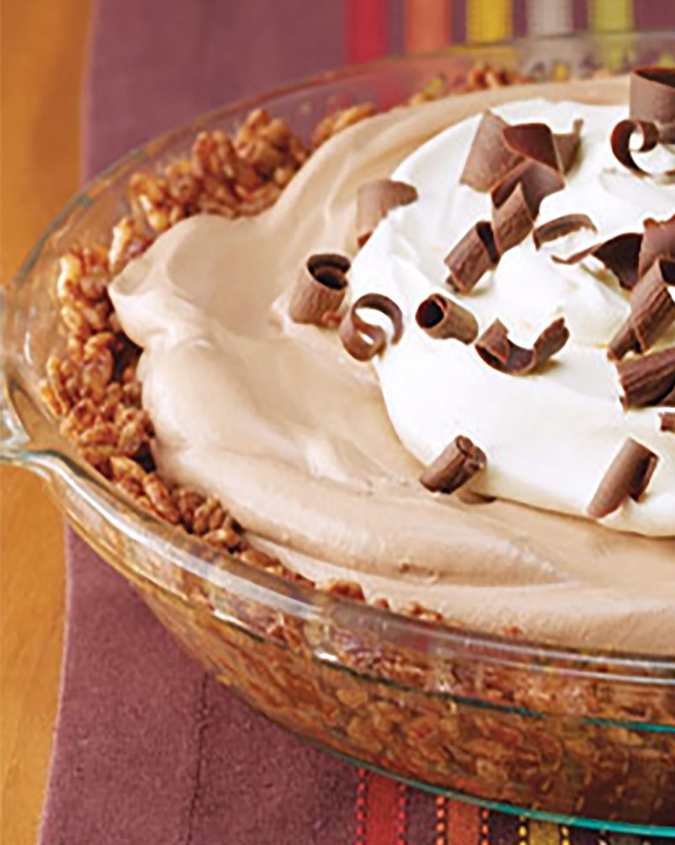 chocolate crunch mud pie in a glass pie dish with whipped cream and chocolate curls on top