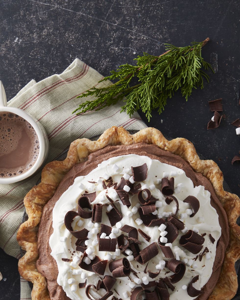 hot chocolate ice box pie in a pie tin with two mugs of hot cocoa next to it