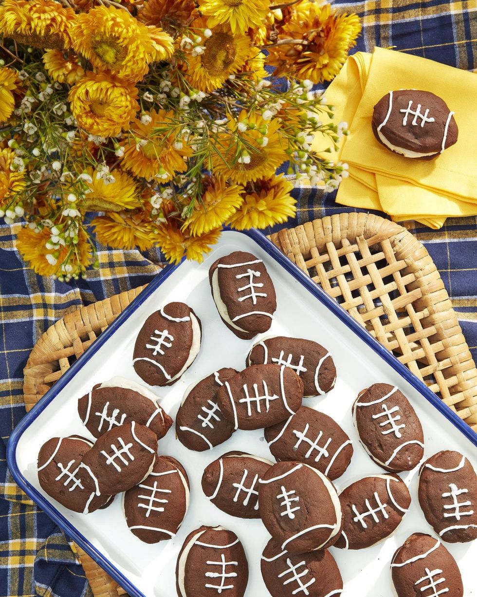 chocolate football whoopie pies with cinnamon cream filling arranged on a white tray with blue trim