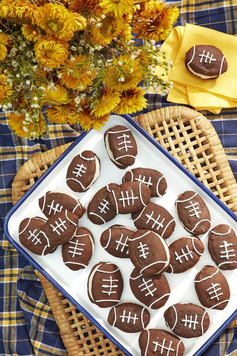 chocolate football whoopie pies with cinnamon cream filling arranged on a white tray with blue trim
