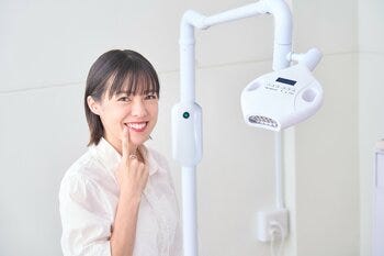 a person smiling and leaning on a white wall