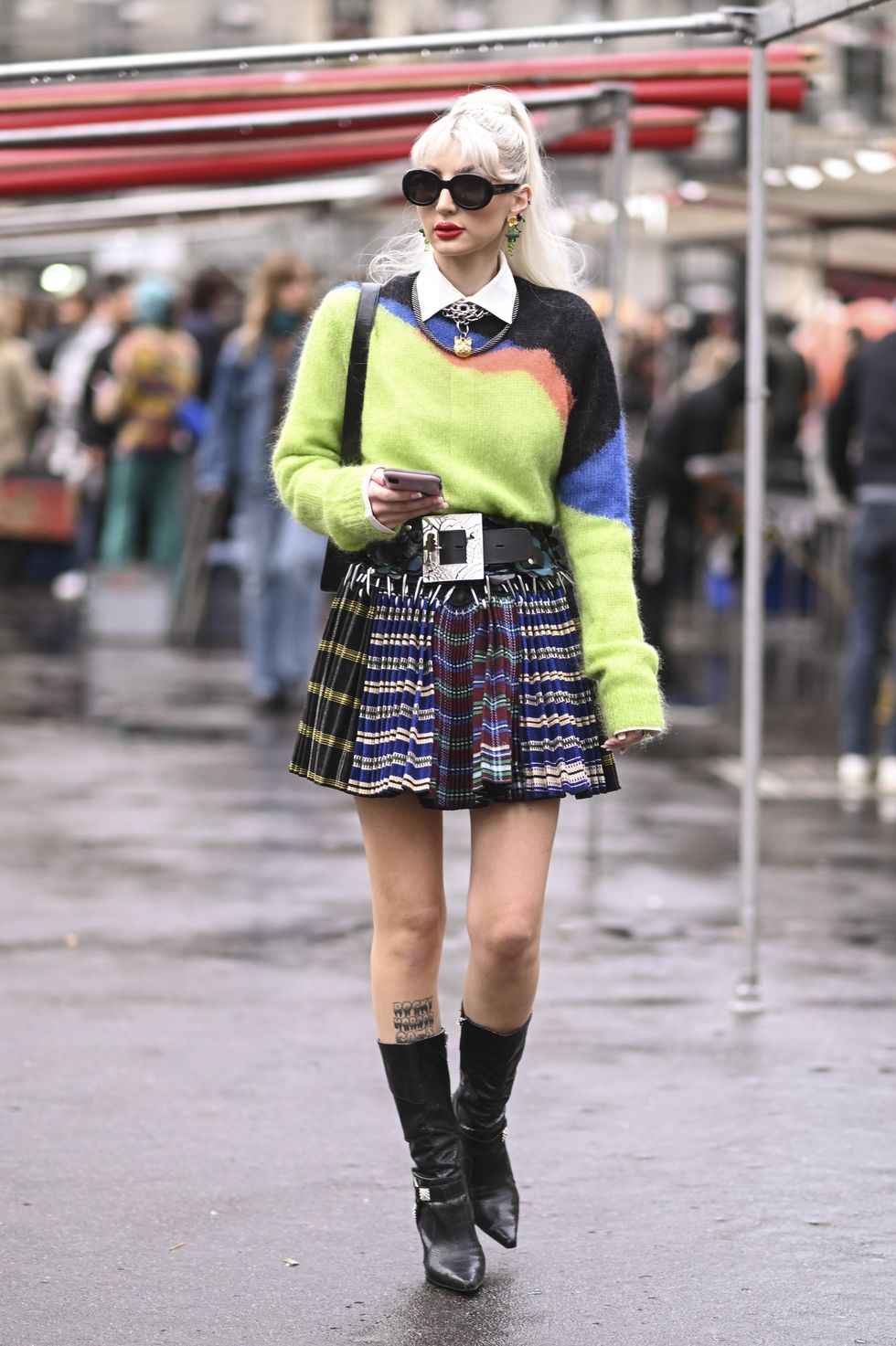 paris, france september 27 a guest is seen wearing a green and black sweater, black silver belt, plaid skirt, black boots and black sunglasses outside the koche show during paris fashion week ss 2023 on september 27, 2022 in paris, france photo by daniel zuchnikgetty images