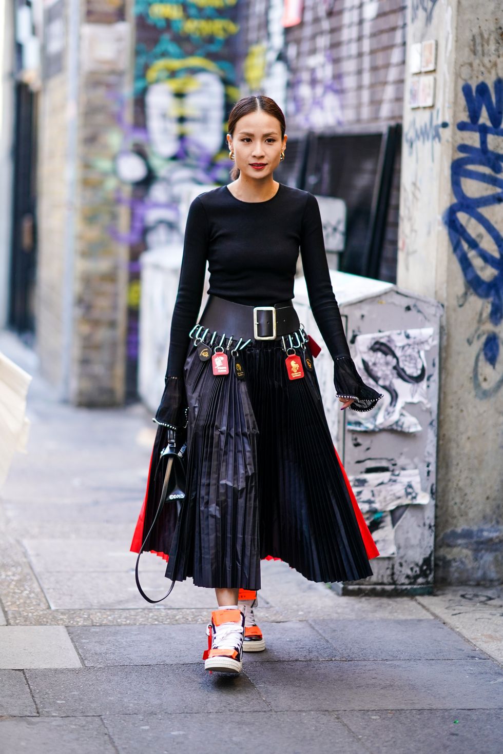 london, england september 14 a guest wears earrings, a black top with flared sleeves, a large leather belt with attached tags from chopova lowena, a pleated skirt, sneakers, during london fashion week september 2019 on september 14, 2019 in london, england photo by edward berthelotgetty images