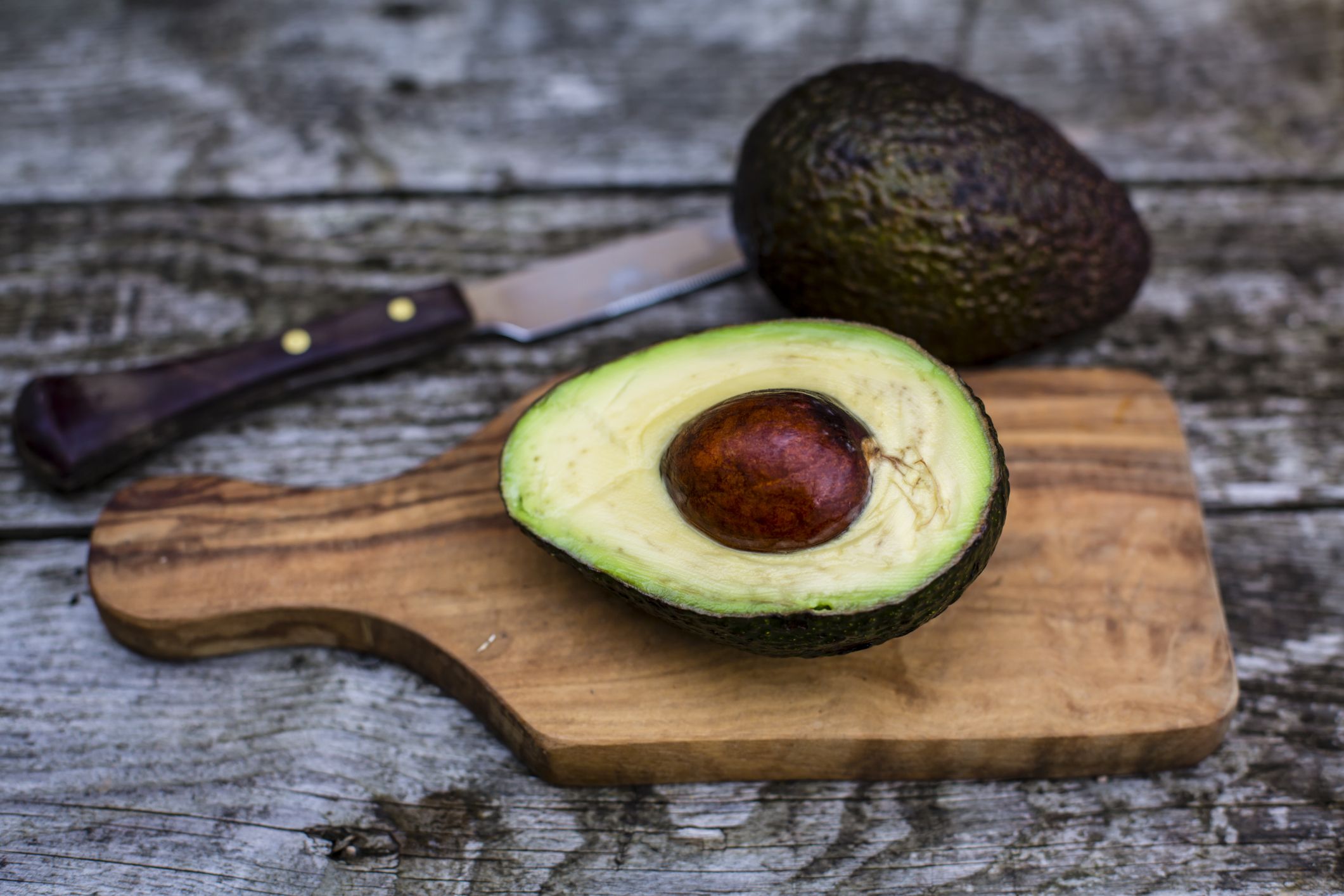 Free Photo  Delicious avocado in a cutting board side view on a wooden