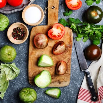 chopped tomatoes and knife on cutting board, fresh vegetables on the table, top view