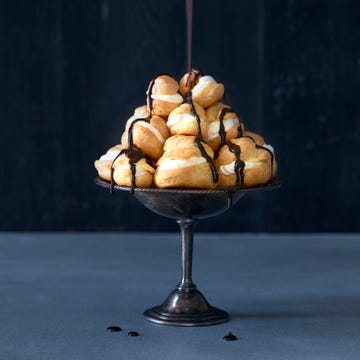 dessert stand of profiteroles being drizzled with chocolate.