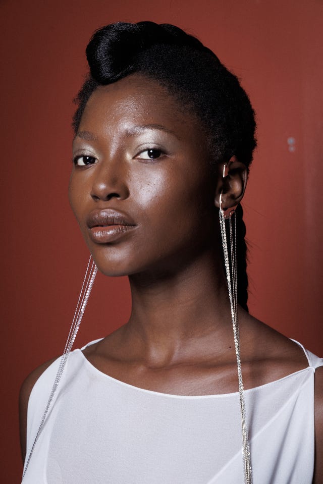 fashion model wearing a highneck white garment with distinctive earrings