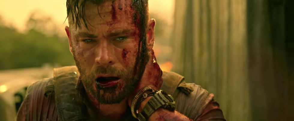 chris hemsworth holds his neck after being shot in netflix movie extraction