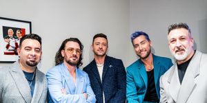 chris kirkpatrick, jc chasez, justin timberlake, lance bass, and joey fatone pose for a photo together while standing, all five men wear suits of different colors