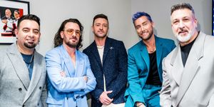 chris kirkpatrick, jc chasez, justin timberlake, lance bass, and joey fatone pose for a photo together while standing, all five men wear suits of different colors