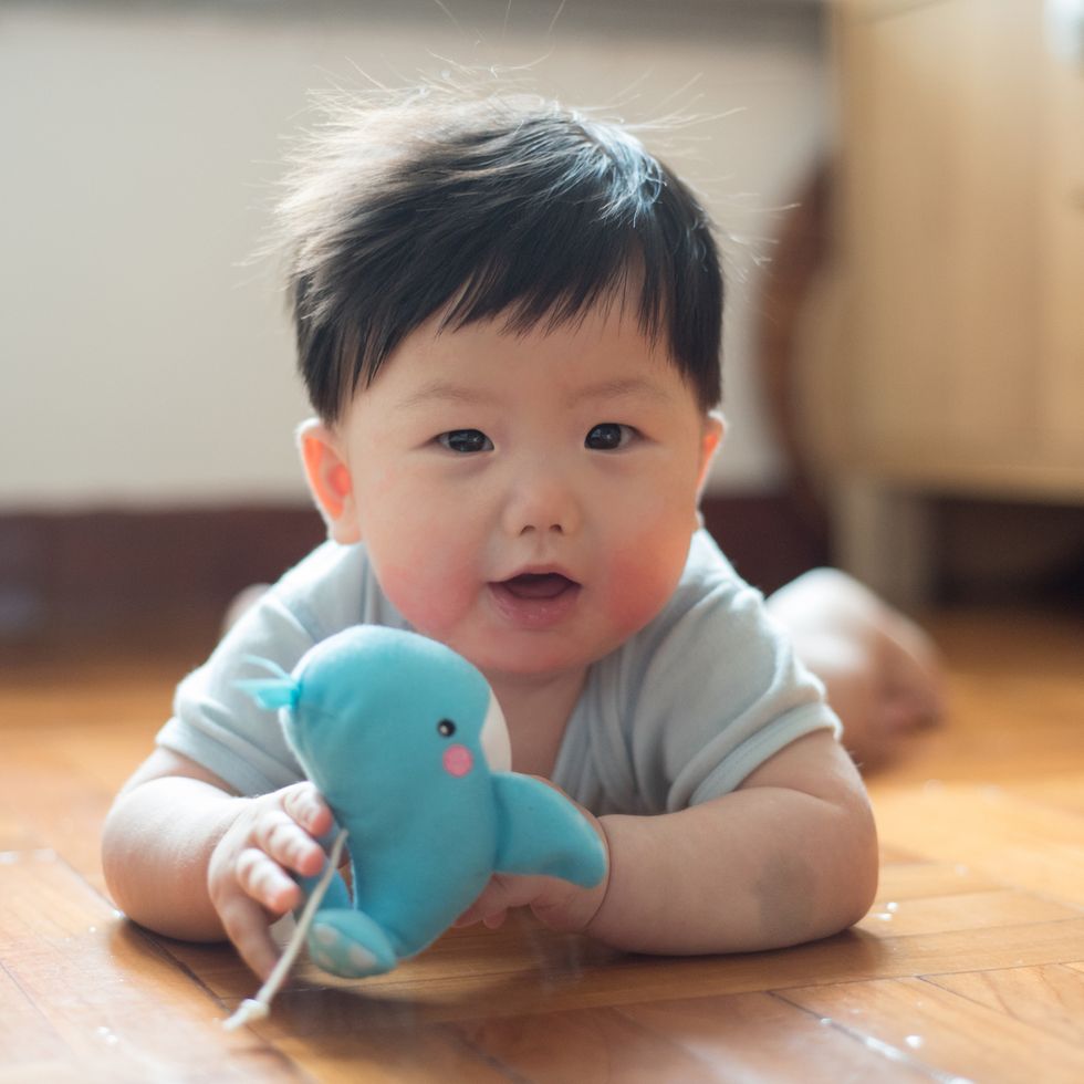christian names boys biblical names 7 months old baby boy playing toy whale while lying on wooden floor