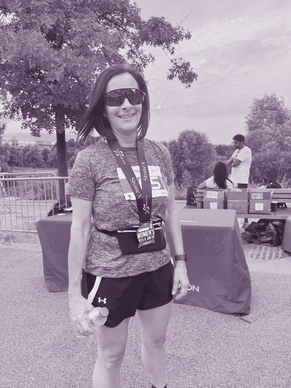 smiling runner standing in a race environment and wearing a medal