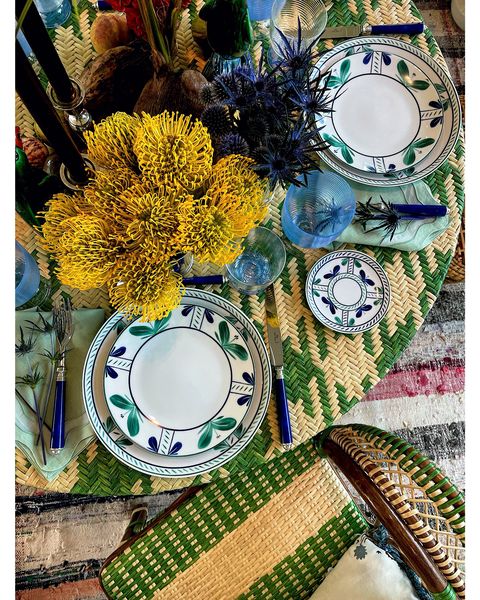a top down shot of a table filled with placemats and patterned plates surrounded by florals