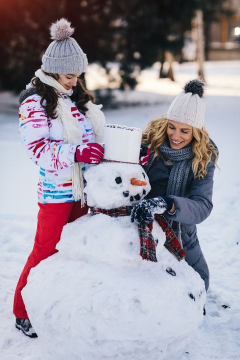 a woman and child building snowman