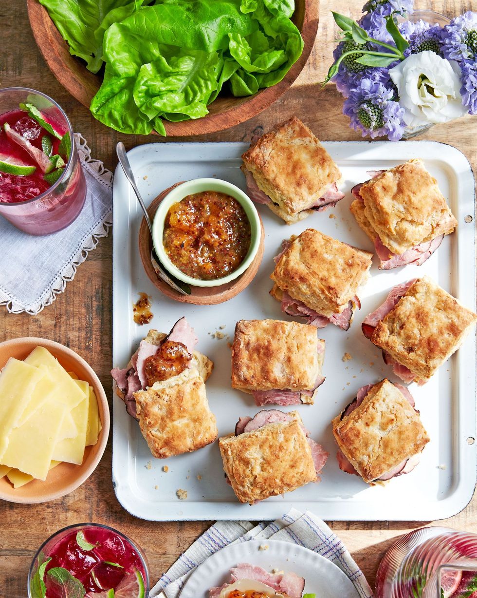 ham biscuit sandwiches arranged on a white serving tray with a small bowl of apricot mustard