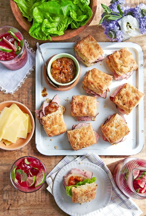 ham biscuit sandwiches arranged on a white serving tray with a small bowl of apricot mustard