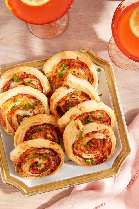 ham and cheese pinwheels arranged on a white square serving plate with gold trim