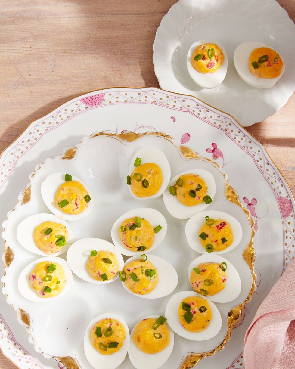 pimiento deviled eggs on a deviled egg plate and topped with sliced green onion
