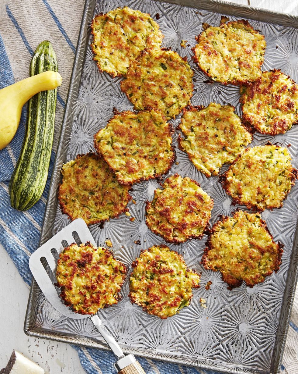 zucchini and pecorino fritters arranged on a sheet pan with a spatula for serving