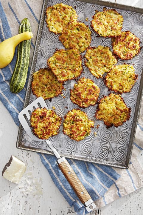 zucchini and pecorino fritters arranged on a sheet pan with a spatula for serving