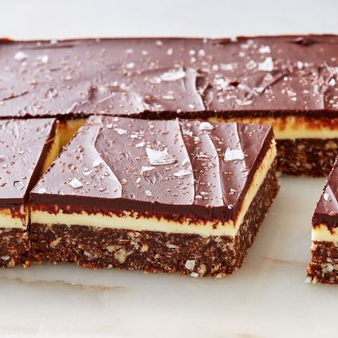 nanaimo bars with coconut, chocolate and graham crackers on a marble countertop