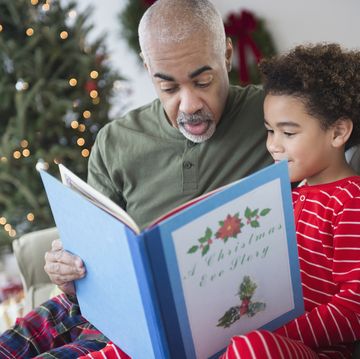 mixed race grandfather reading to grandson at christmas