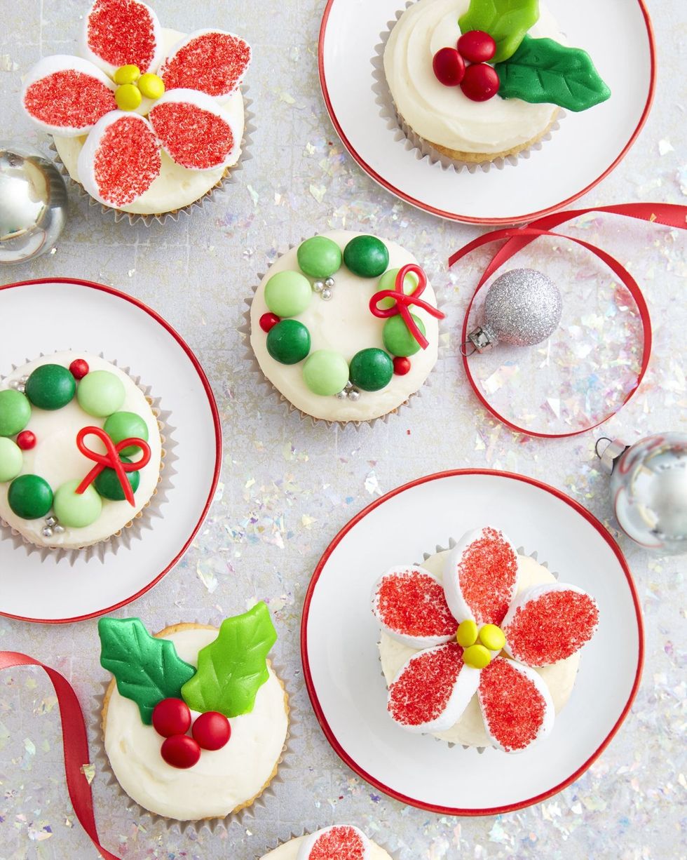 cupcakes topped with vanilla frosting and various candies to look like holly and wreaths and poinsettias
