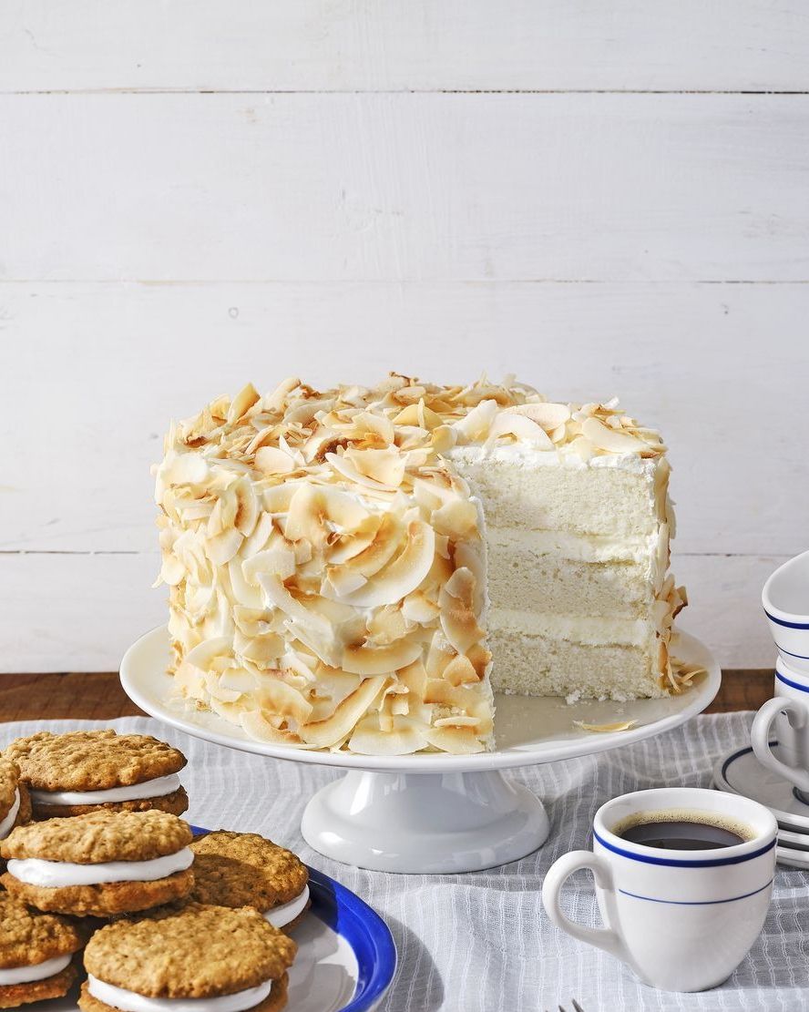 three layer white cake covered in lightly toasted coconut flakes