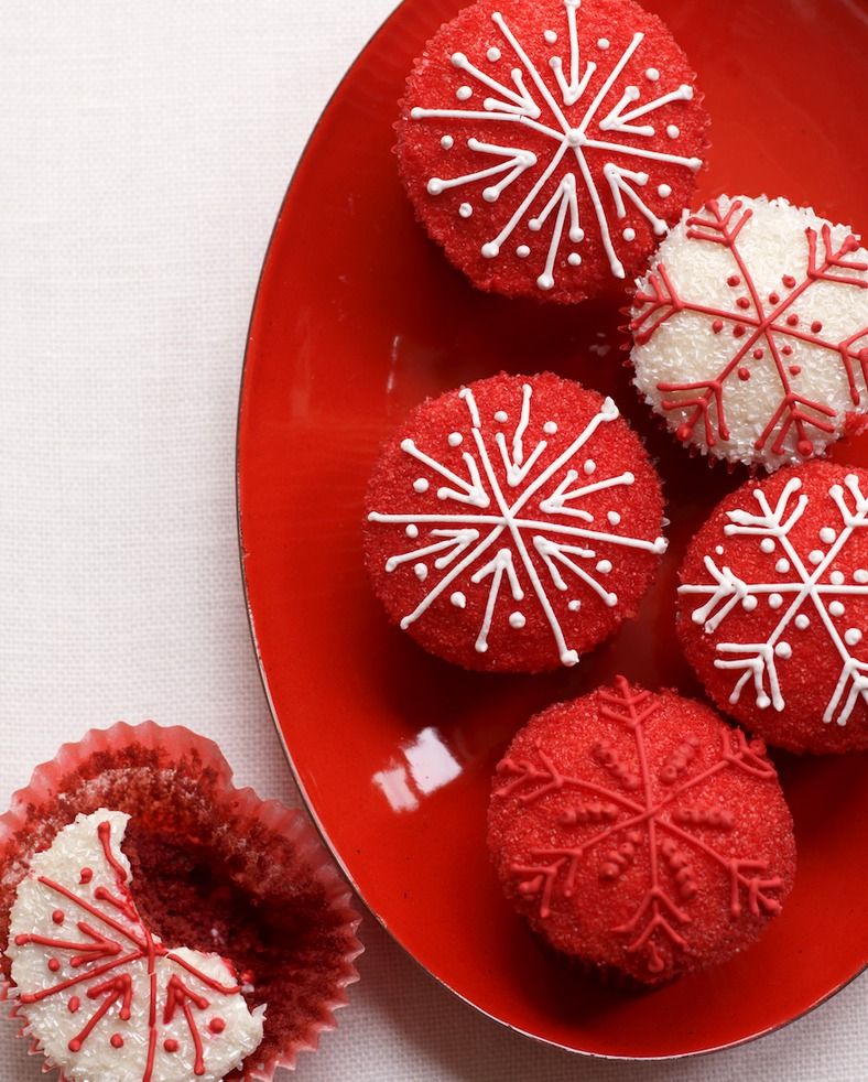 red velvet cupcakes topped with red or white sugar sprinkles and thin snowflake designs piped on top