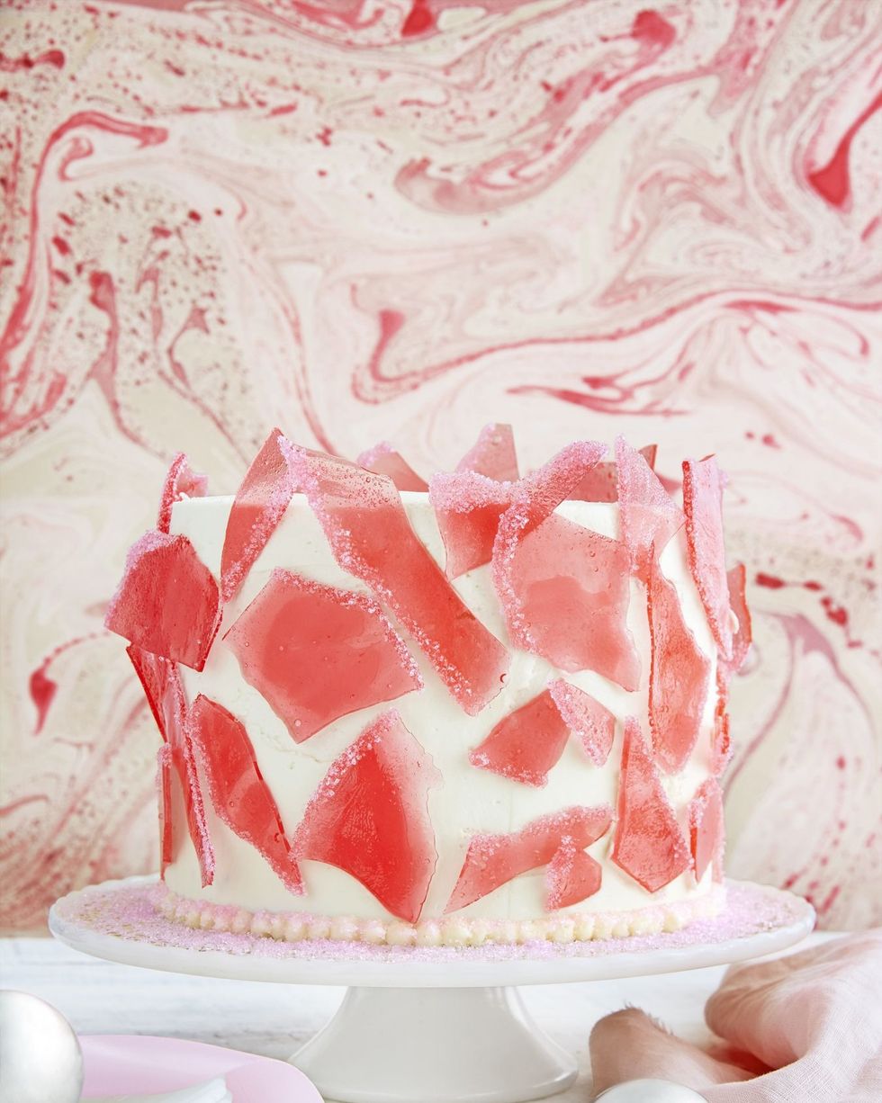layer cake with white frosting and covered in broken pieces of sugar candy resembling stained glass