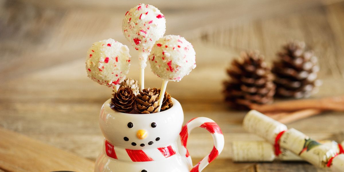 close up of peppermint cake pops sitting in snowman mug with party poppers and pine cone decorations for the holidays